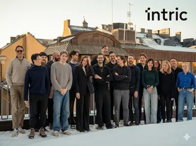 Gruppe von Personen auf verschneiter Dachterrasse; im oberen rechten Bildbereich steht der Schriftzug „intric“.